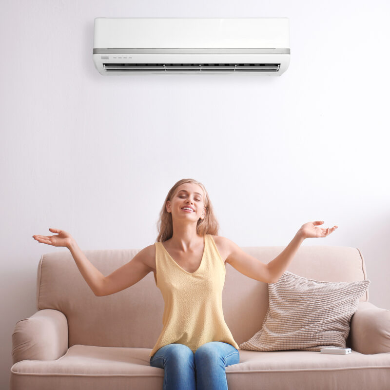 Young woman comfortable near air conditioner at home