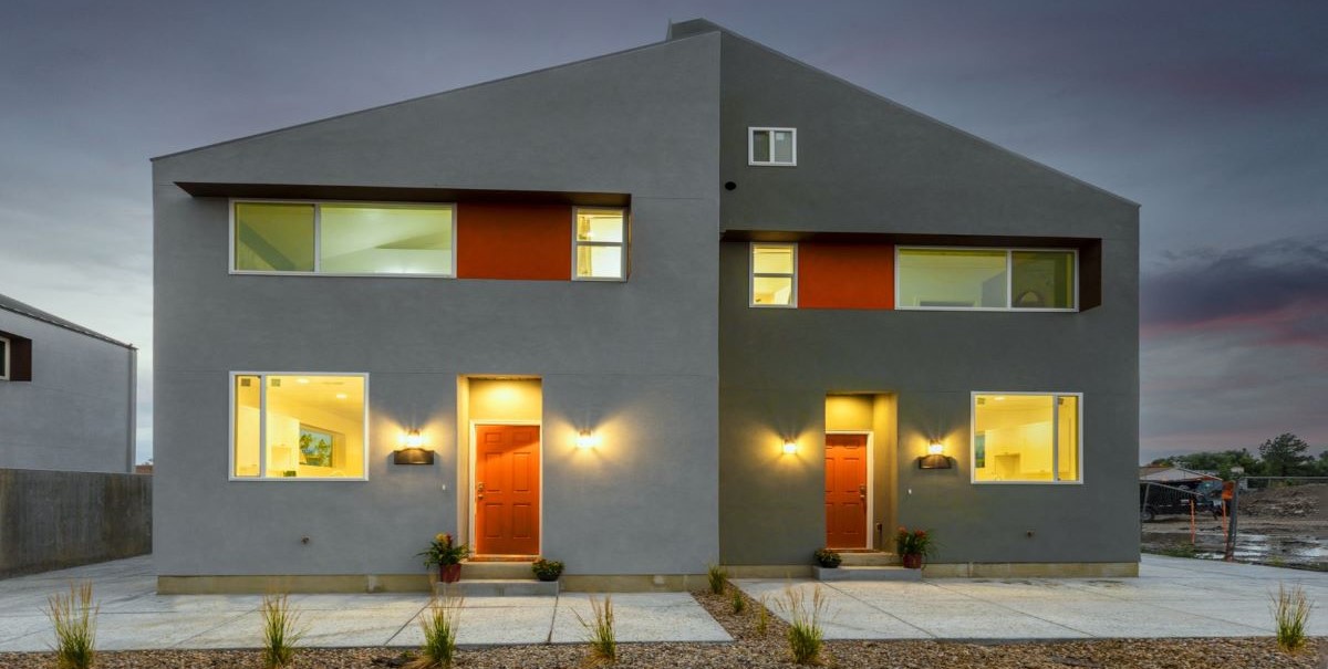 Exterior of duplex with modern styling in xeriscape setting; glows warmly against dusk sky – photo