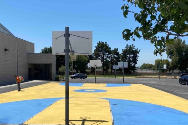 outdoor basketball court in schoolyard; bright blue and yellow markings on the court - photo