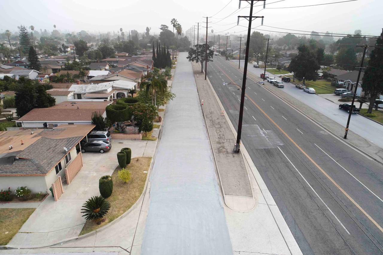 aerial view of asphalt street; access road running alongside has gray cool-pavement coating to reduce temperatures - photo