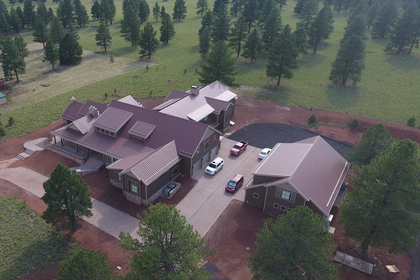 aerial view of sprawling home of SIP construction, surrounded by large outbuilding, fields and pines - photo