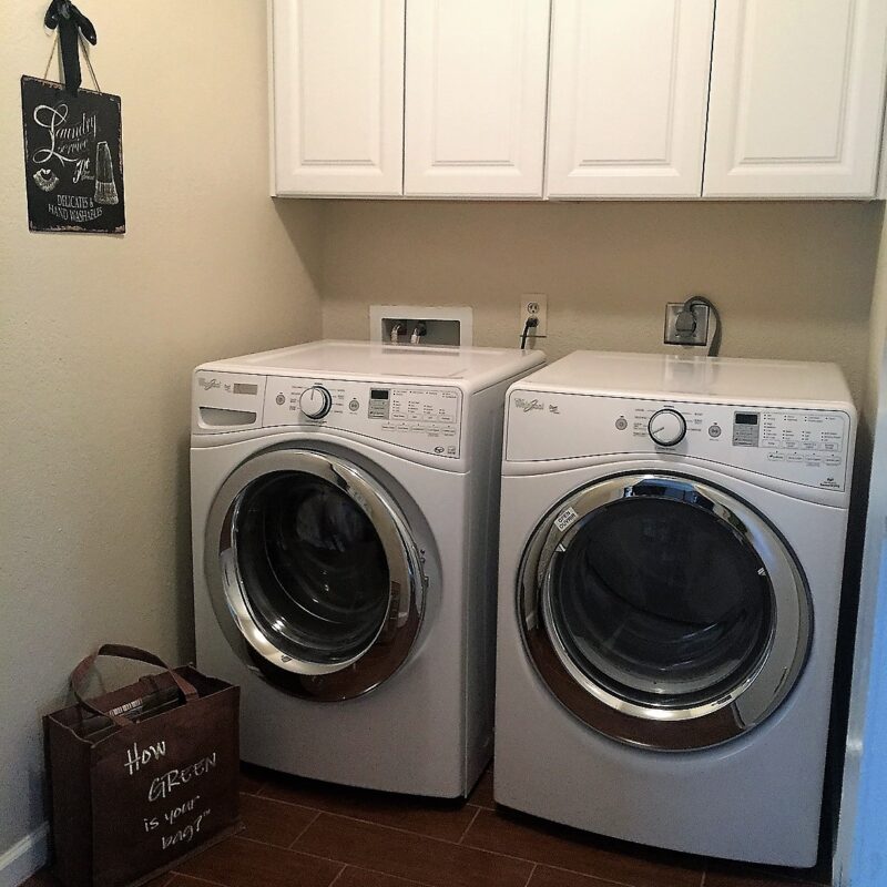 ENERGY STAR washer and dryer dide-by-side in residential laundry room; tote bag sits on the tiled floor reads "How green is your bag?" - photo