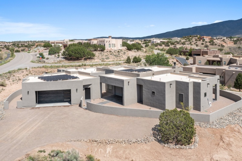 exterior view of large, moder adobe-style house in desert setting, solar panel on roof; SIP panel suppliers: Premier Building Systems 