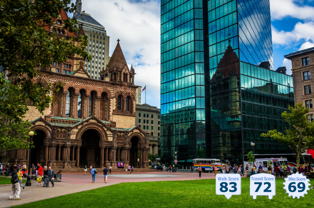 outdoor view of historic and modern building juxtaposed in a walkable city, with many pedestrians and greenspace in the foreground and transit buses - photo