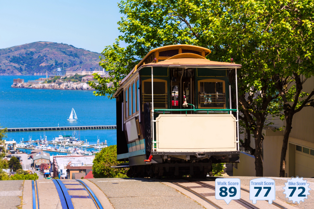 Beautiful image of street with Cable car cresting a hill a view of San Francisco Bay with sailboats and Alcatraz in the background; scrubby wild lands of Marin in the far background - photo