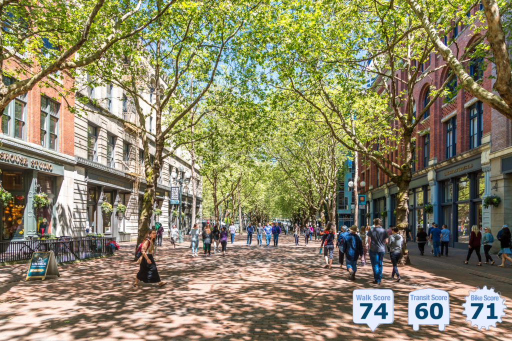 outdoor view down brick-paved street with leafy green trees arcing overhead; traffic is blocked and pedestrians walk on sidewalks and in the street, as it is blocked to auto traffic. Street is lined with shops having residences or offices on upper floors - photo